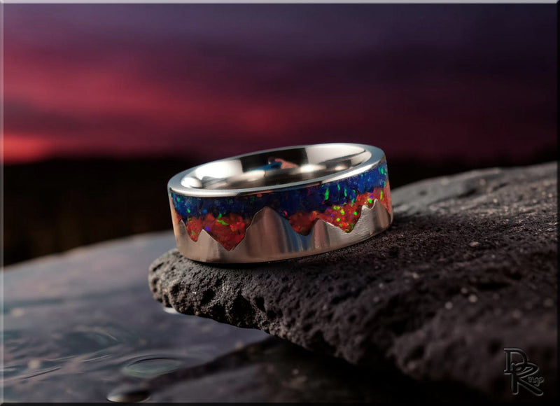 Close-up of a metal pattern rings with blue and red intricate design placed on black textured stone surface