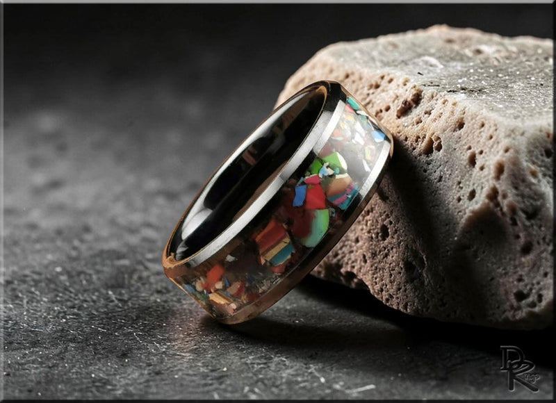 Ceramic ring collection featuring a polished ceramic ring with colorful crushed stone inlay resting on a textured stone surface