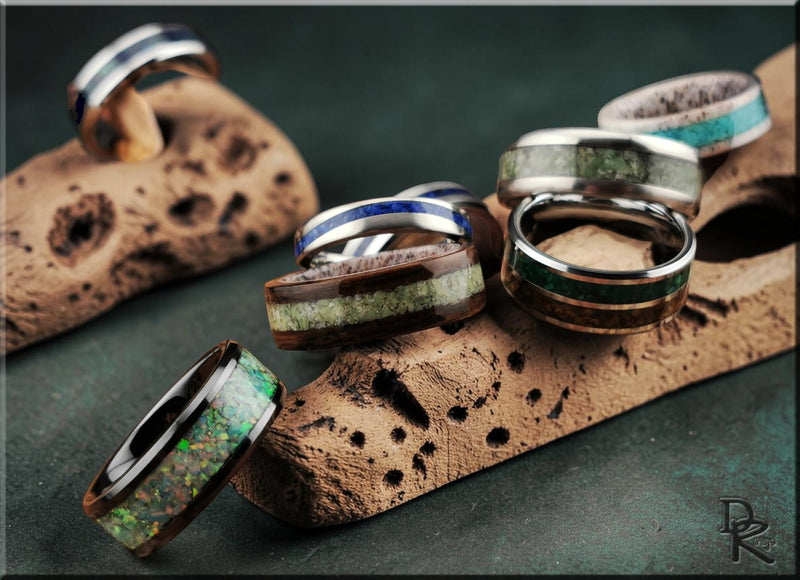 Close-up of featured products including three stylish rings with unique inlays displayed on a stone surface