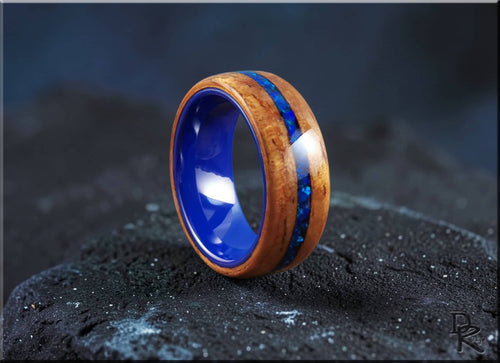 Koa wood ring with opal and ceramic blue inlay by DR Rings on black textured surface