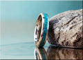 DR Rings silver ring with inlay featuring turquoise stone detail beside textured rock and water reflection