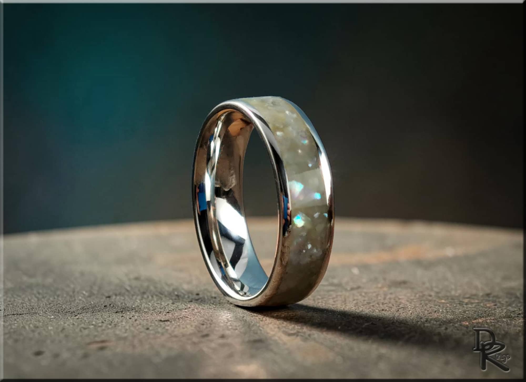 Sterling silver ring with pearl inlay by DR Rings displayed on a textured surface