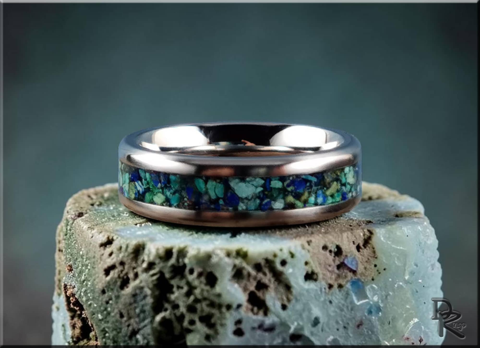 Titanium ring with azurite inlay showcasing blue and green stones on a textured rock background