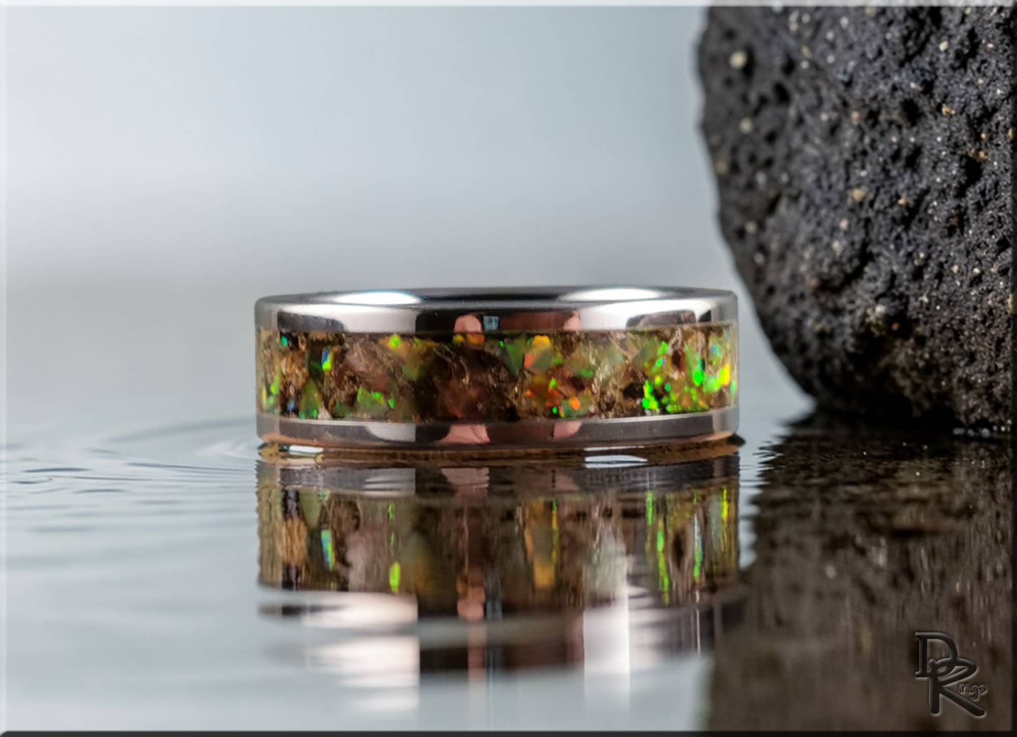 DR Rings titanium ring with inlay featuring green and brown opal design on reflective surface