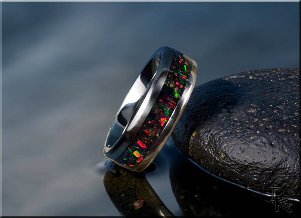 DR Rings titanium ring with opal inlay featuring vibrant red and green flashes on a reflective surface