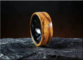 Elegant wood ring on ceramic core with smooth polished finish displayed on textured stone