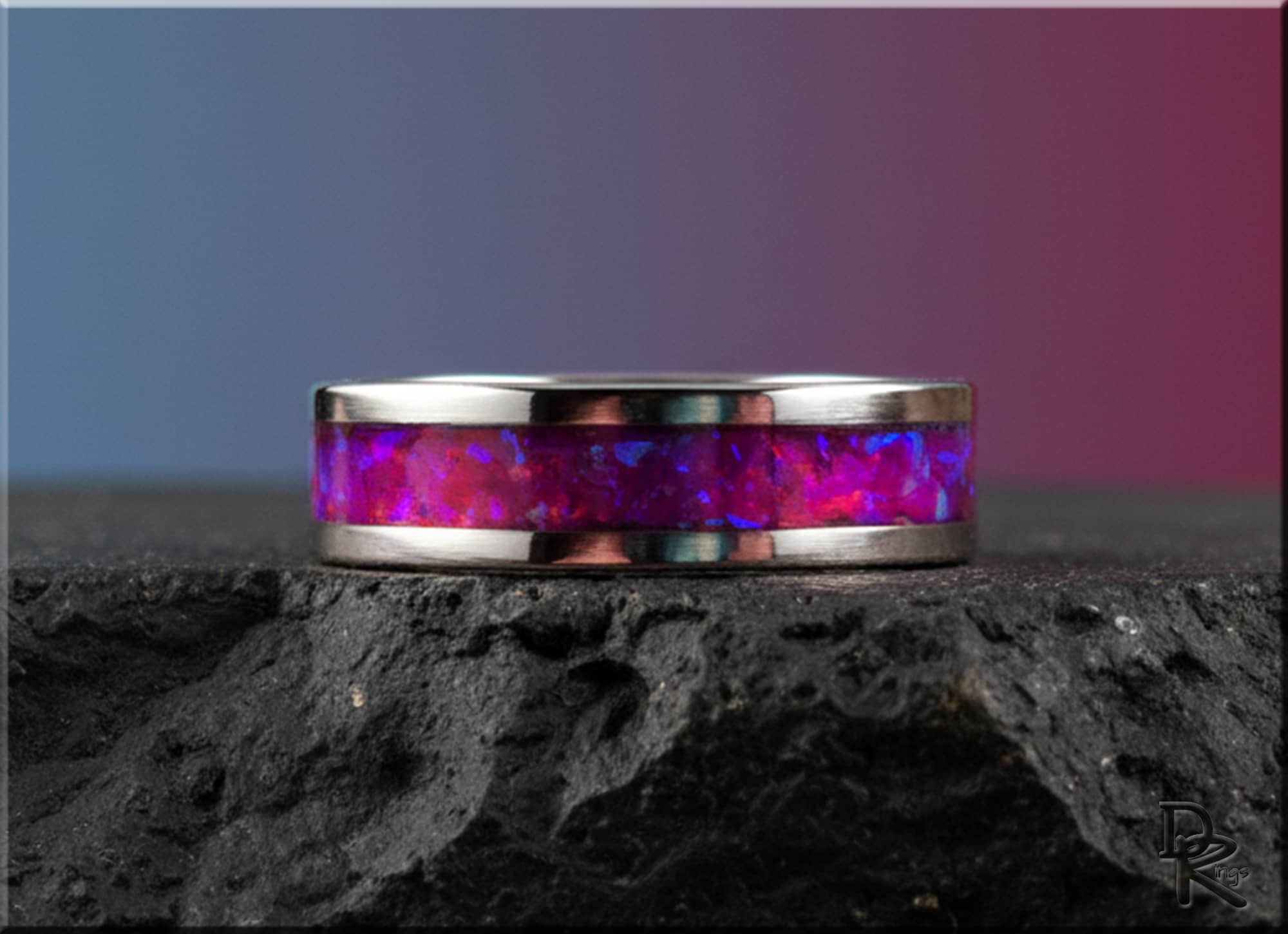 Cobalt chrome ring with opal inlay featuring vibrant purple and pink hues on dark stone surface