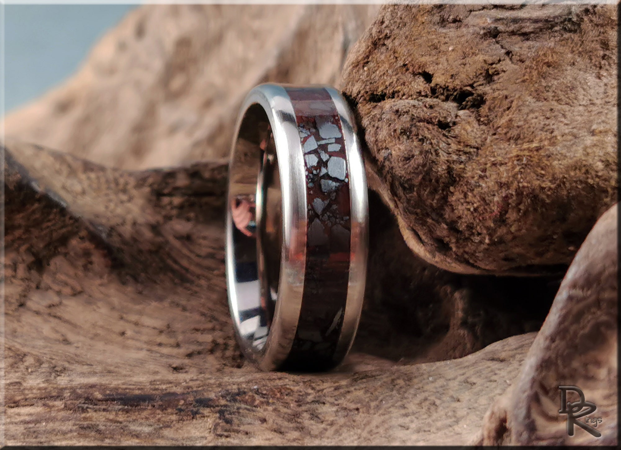 DR Rings titanium smart ring with dark patterned inlay and polished silver edges on wood background