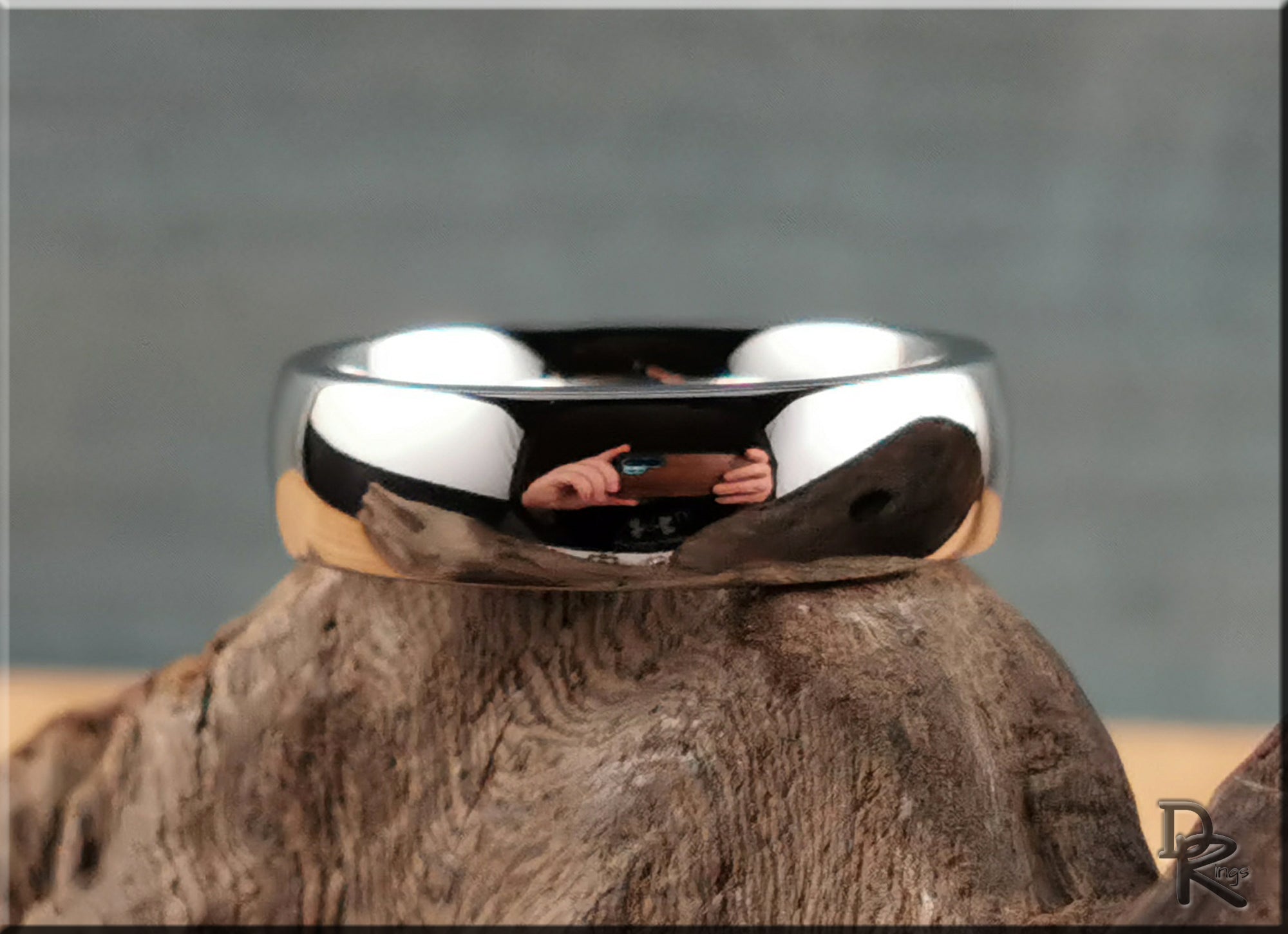 Domed cobalt ring with a polished reflective surface from DR Rings displayed on textured wood