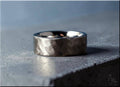 DR Rings hammered titanium ring with textured finish on a gray concrete surface