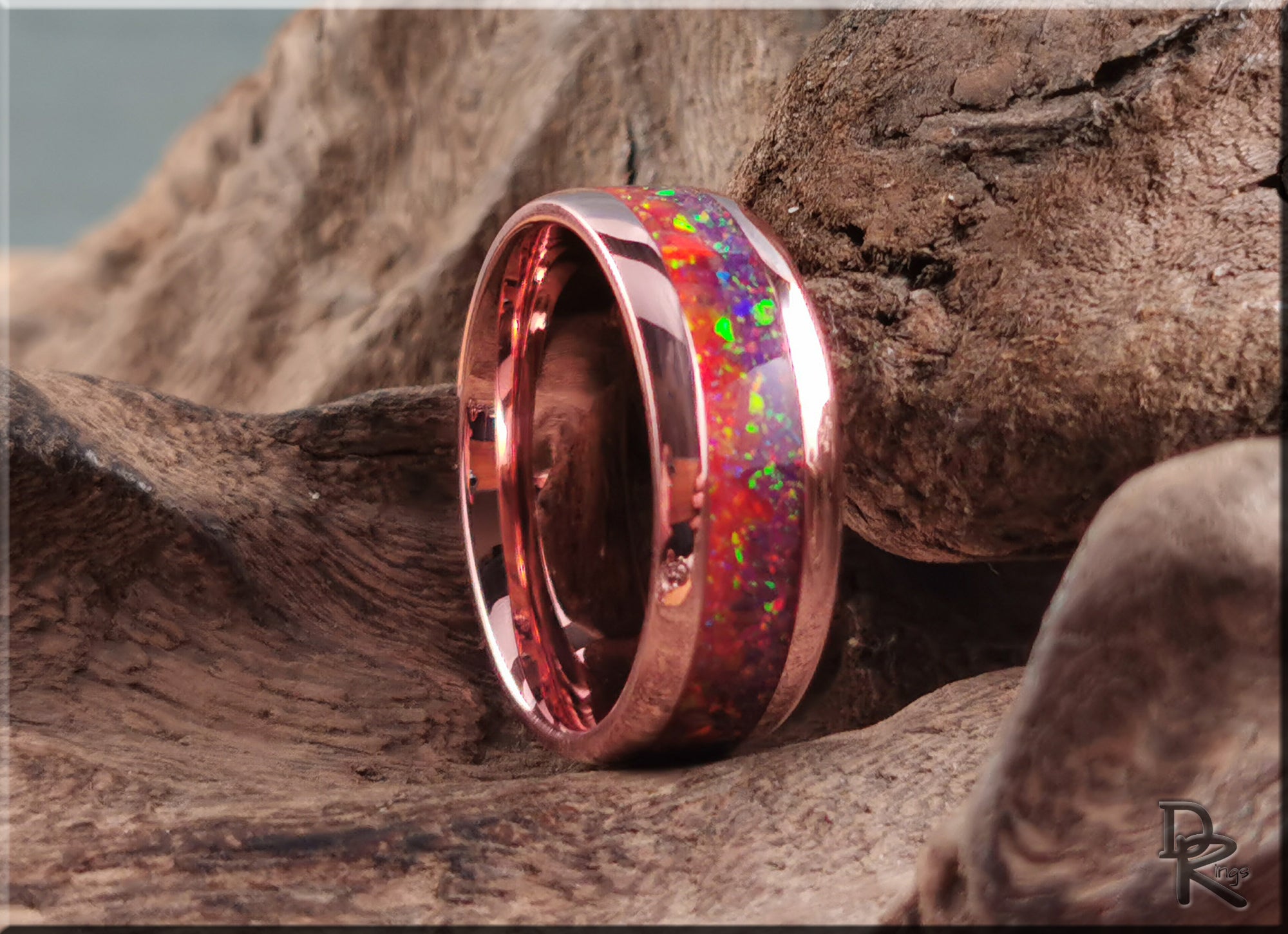 Brushed tellurium copper ring with opal inlay showing vibrant colors set against rustic wood background