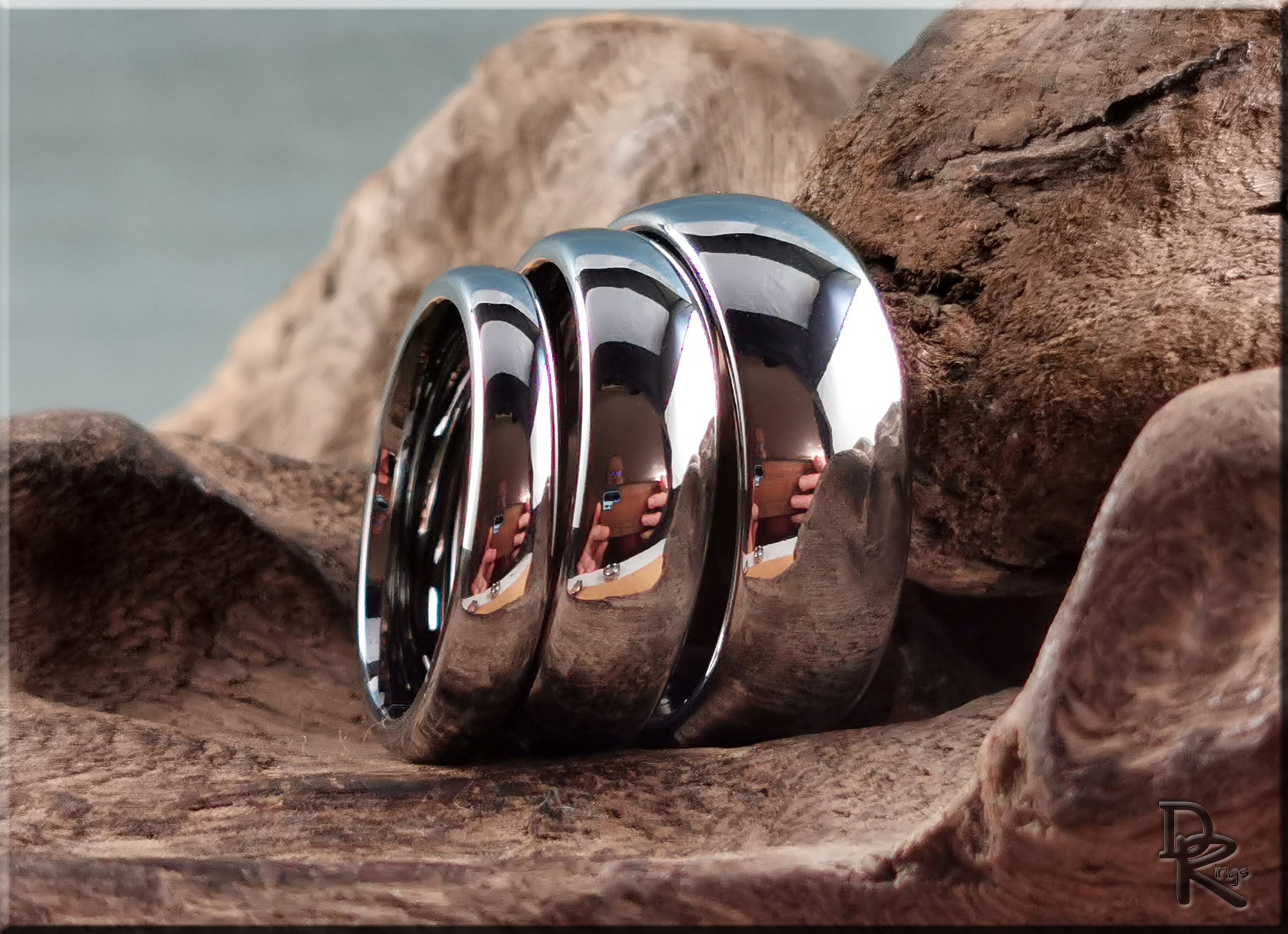 Set of three shiny domed tungsten rings by DR Rings displayed on natural textured rock