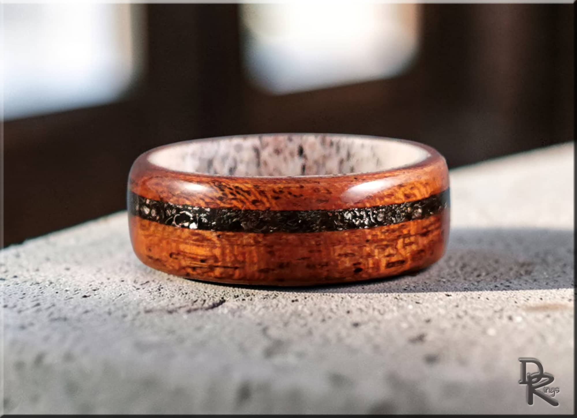 Wood ring with meteorite inlay on deer antler core by DR Rings displayed on stone surface