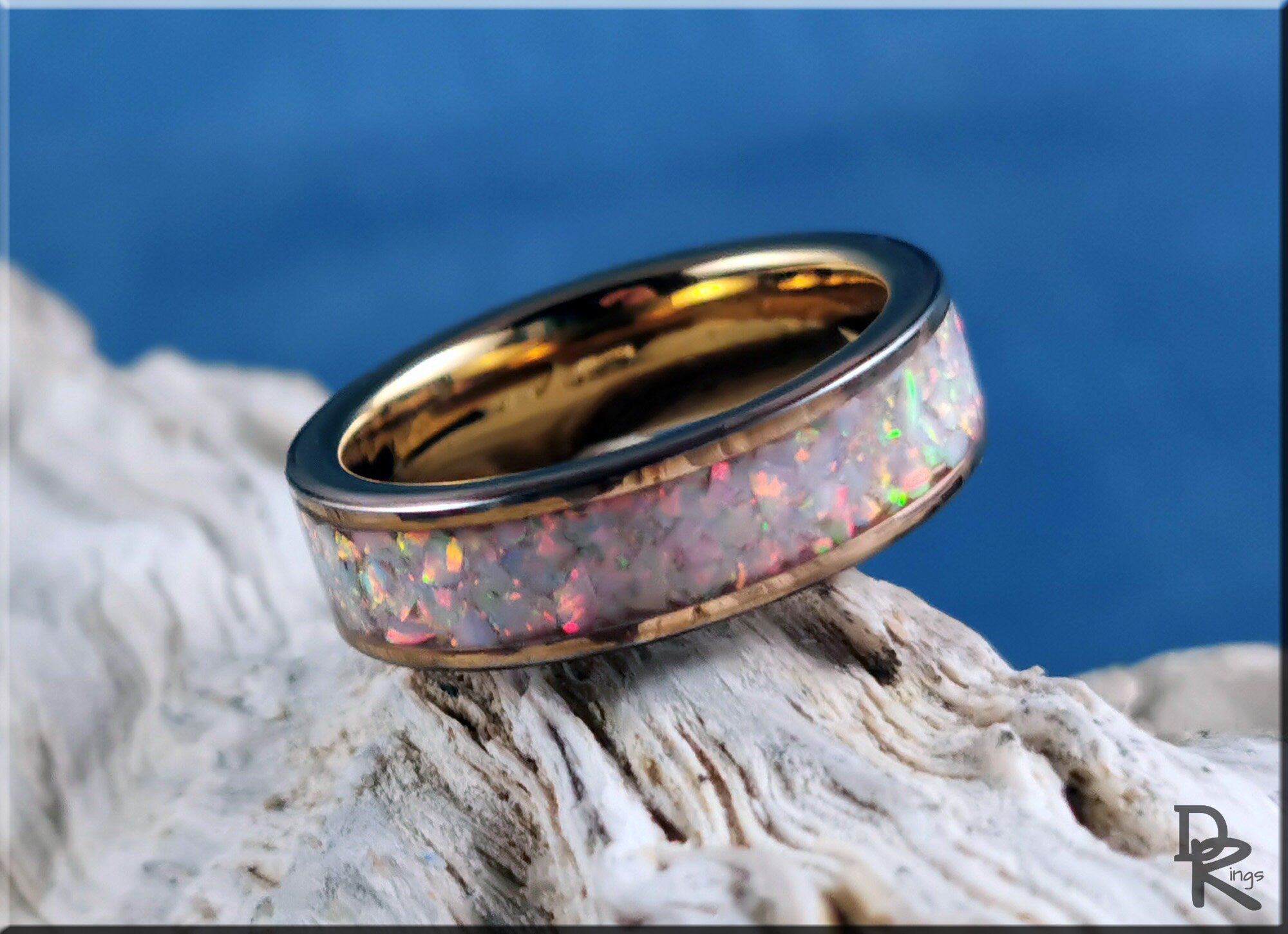 Rose gold tungsten ring with opal inlay featuring iridescent colors on textured background