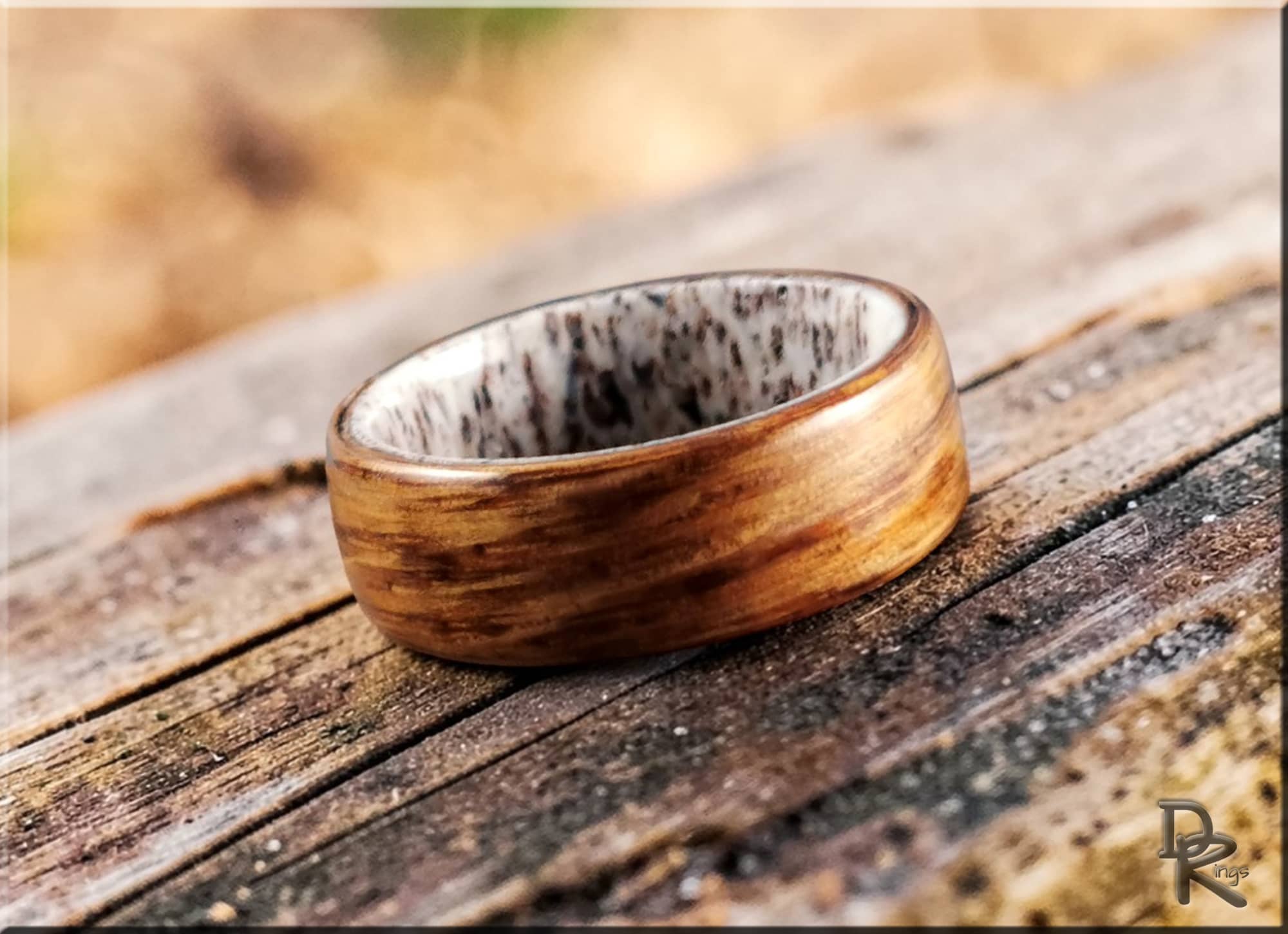 Oak wood ring on antler with smooth finish placed on rustic wooden surface by DR Rings