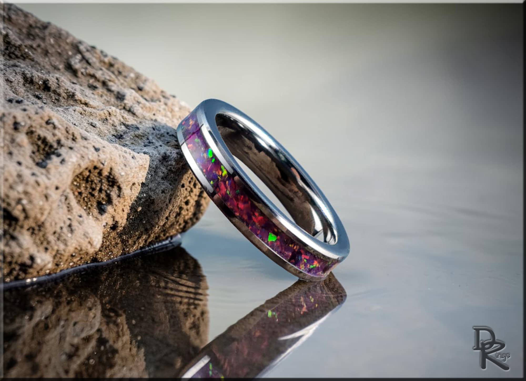 DR Rings polished silver band ring opal inlay with vibrant red and green colors on rock by water