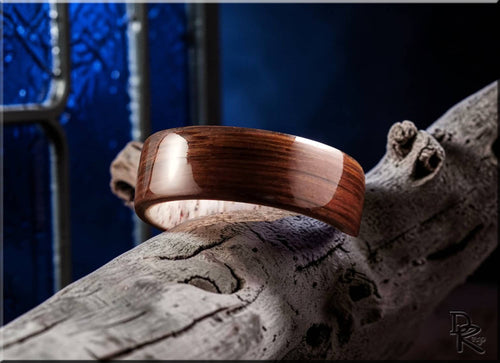 Bog oak wooden ring with polished finish displayed on rustic driftwood by DR Rings