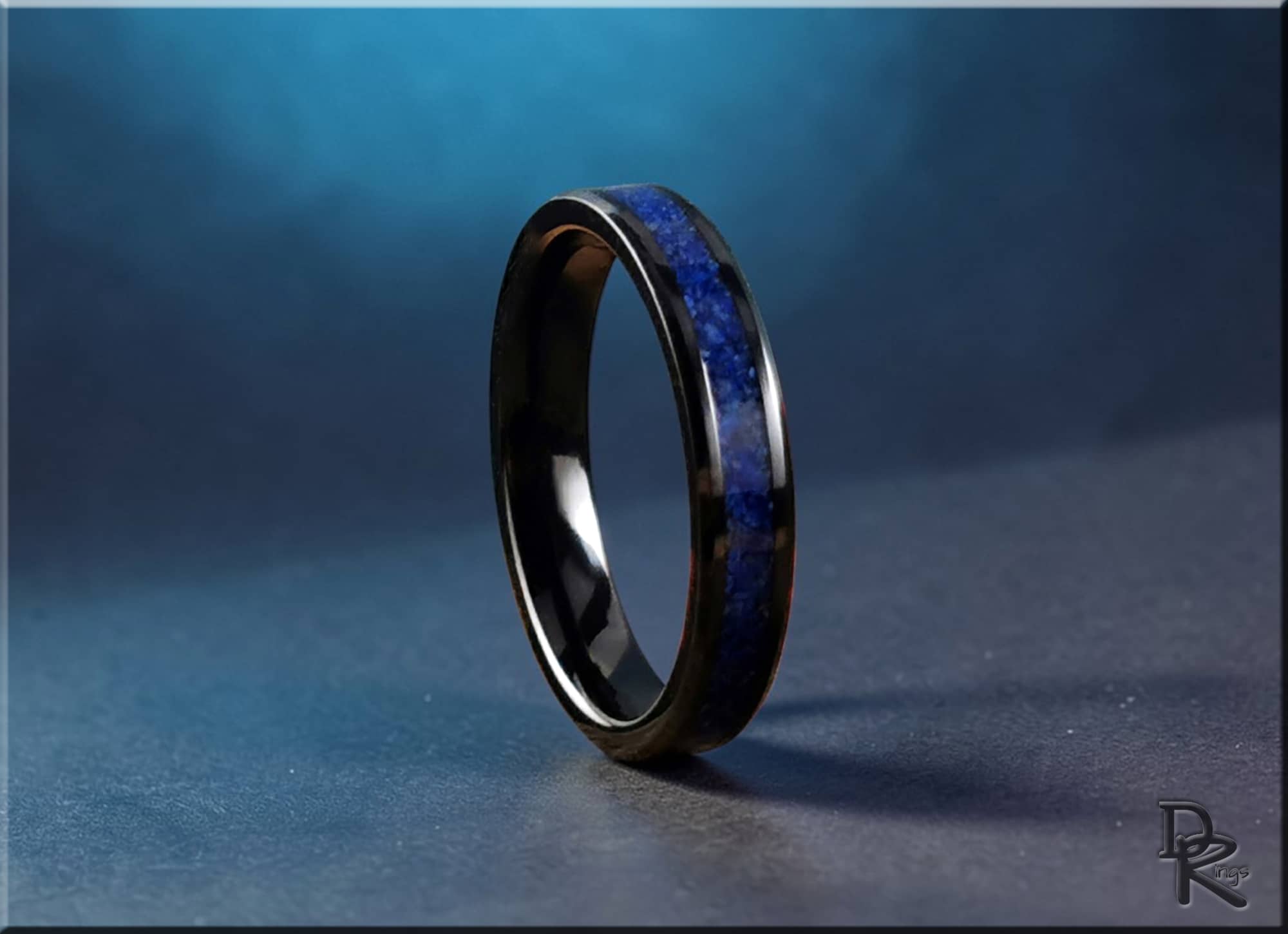 DR Rings black ceramic ring with lapis stone inlay on textured surface with blue background