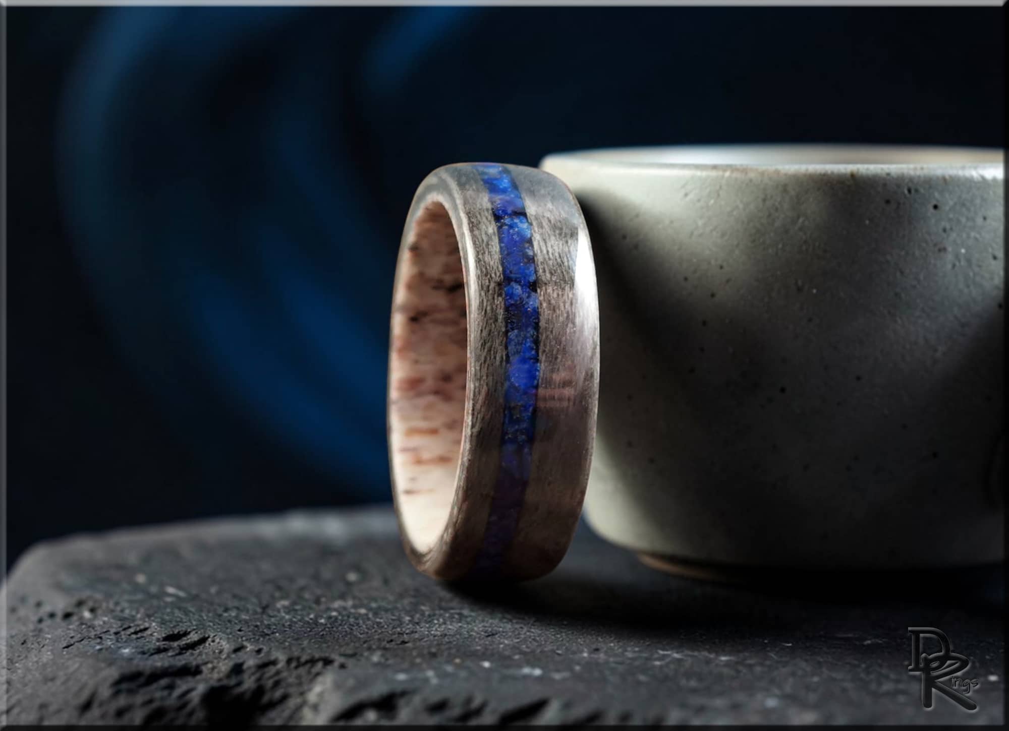 DR Rings wooden ring with a blue lazuli lapis inlay placed beside a gray ceramic cup