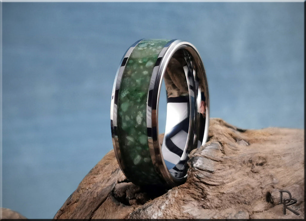 Tungsten carbide ring with inlay featuring a green stone set on a wooden background by DR Rings