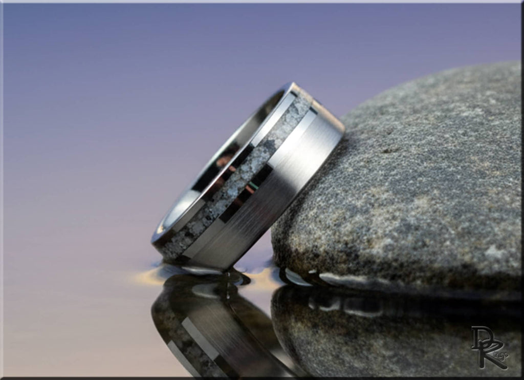 Tungsten carbide ring with moonstone inlay displayed on stone with water reflection
