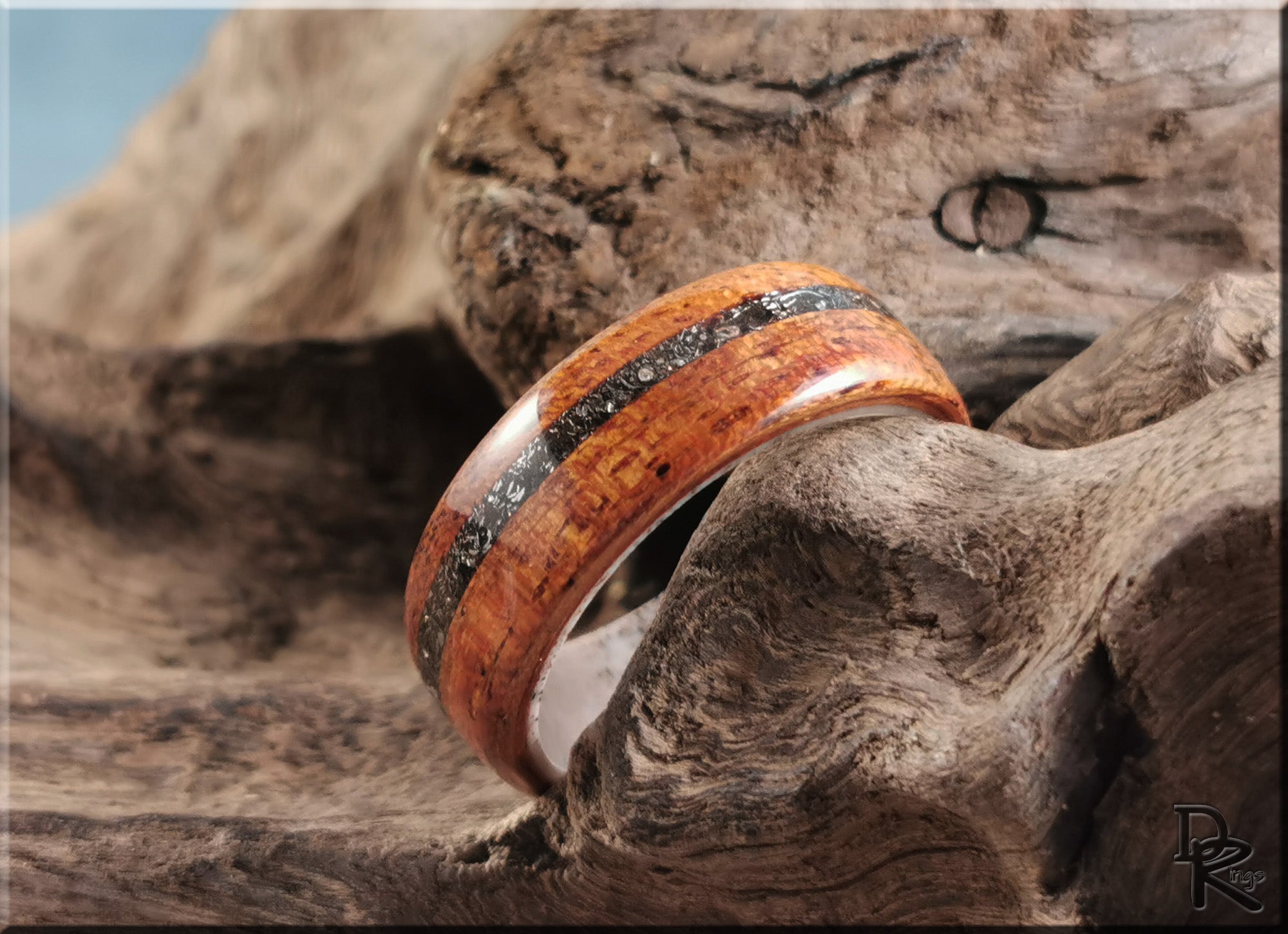 Wood ring with meteorite inlay on deer antler core by DR Rings with polished finish on wooden background