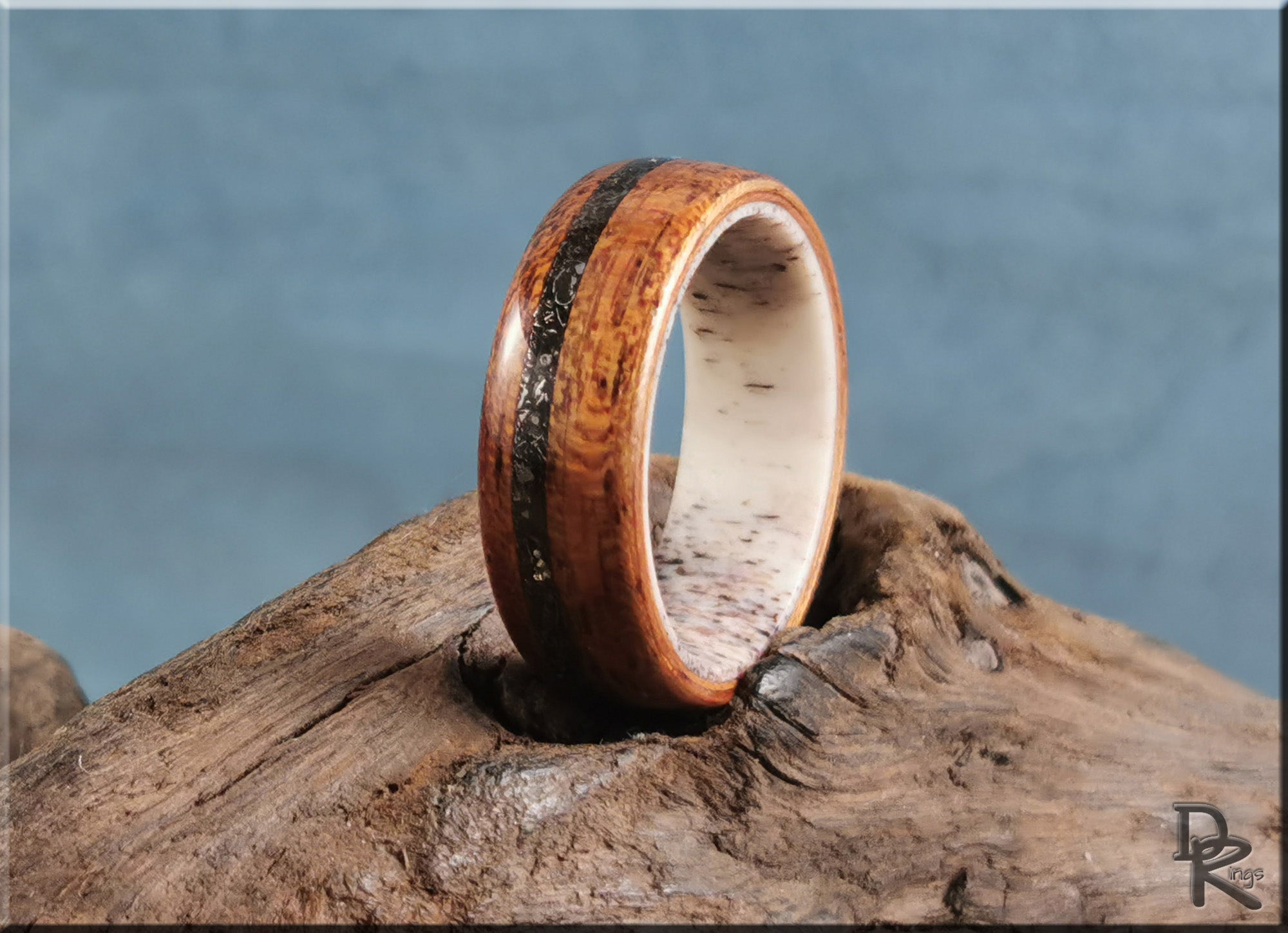 Wood ring with meteorite inlay on deer antler core displayed on rustic wood background by DR Rings
