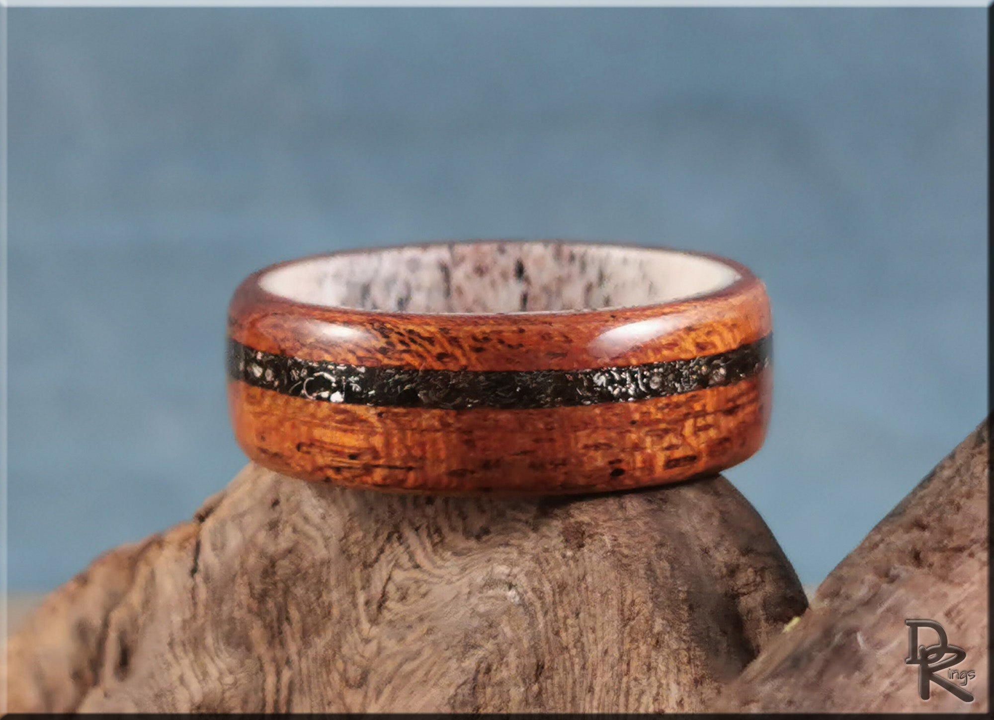 Wood ring with meteorite inlay on deer antler core by DR Rings displayed on natural wood surface