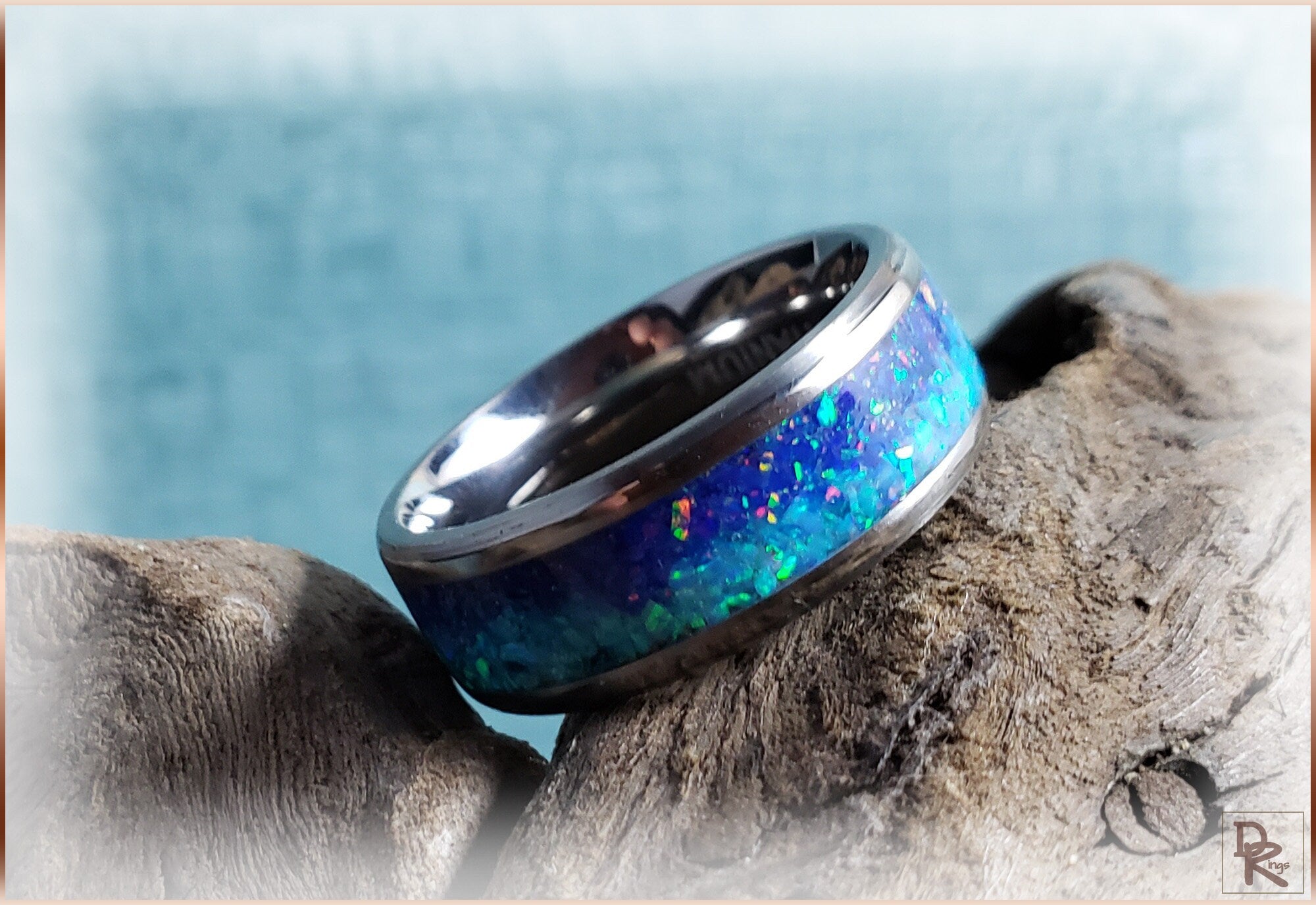 DR Rings titanium ring with opal blue iridescent inlay resting on textured wood surface