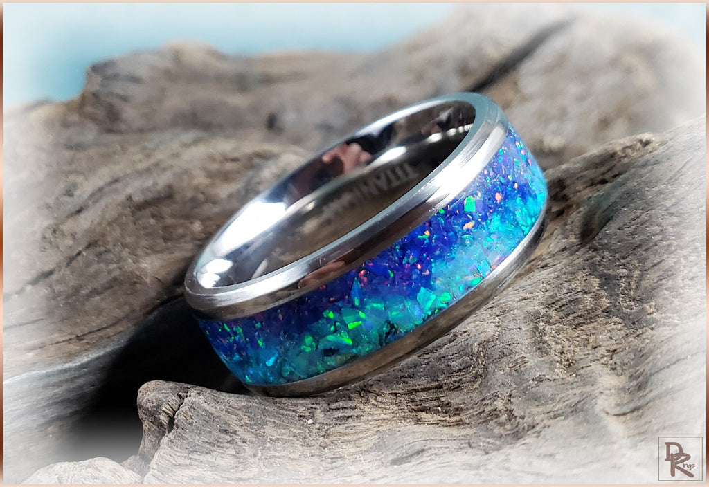 DR Rings titanium ring with opal inlay showcasing vibrant blue and green colors on rustic wood
