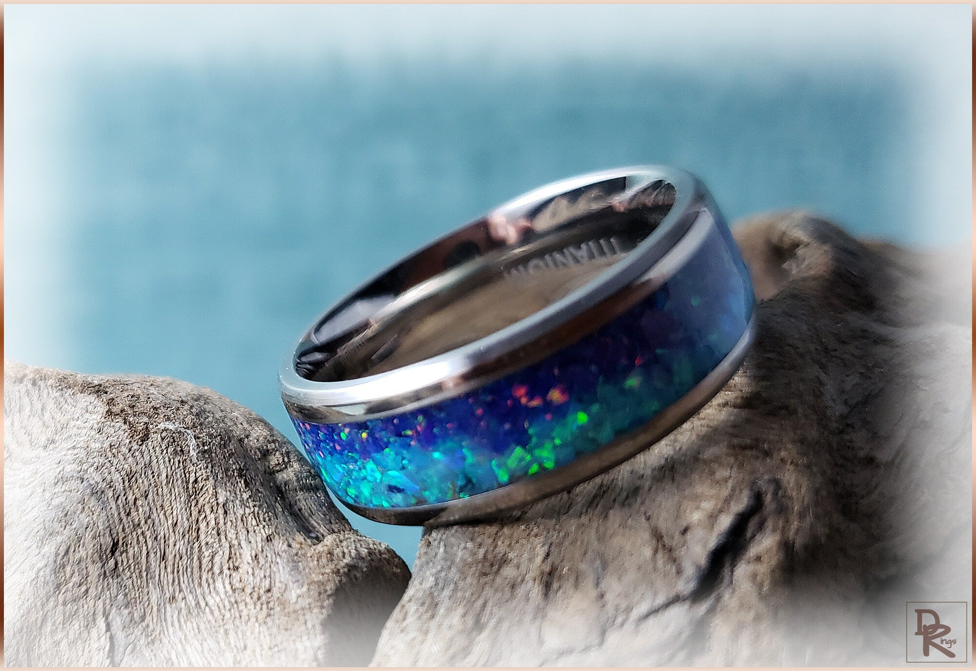 DR Rings titanium ring with opal blue green shimmer design on rustic wooden surface
