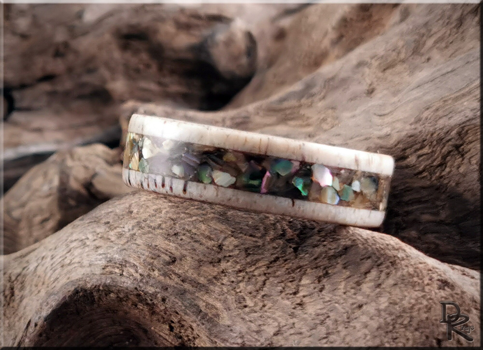 Antler ring with abalone inlay featuring multicolor shell pieces on natural wood background by DR Rings