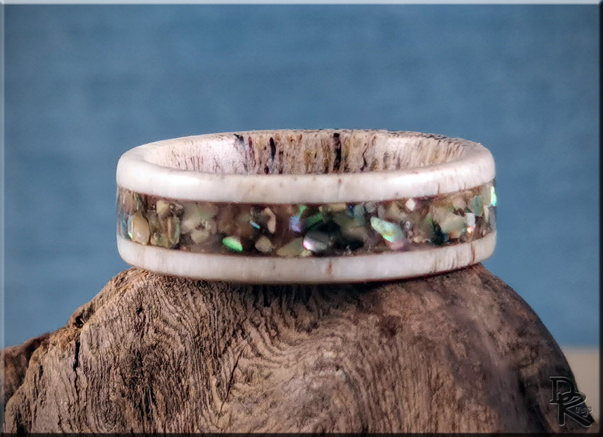 Antler ring with abalone inlay featuring natural earthy tones by DR Rings displayed on rustic wood