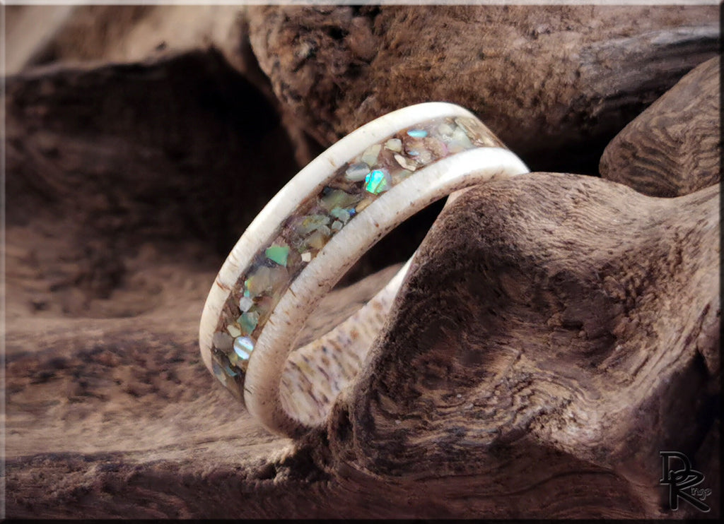 DR Rings antler ring with abalone inlay resting on rustic wood background