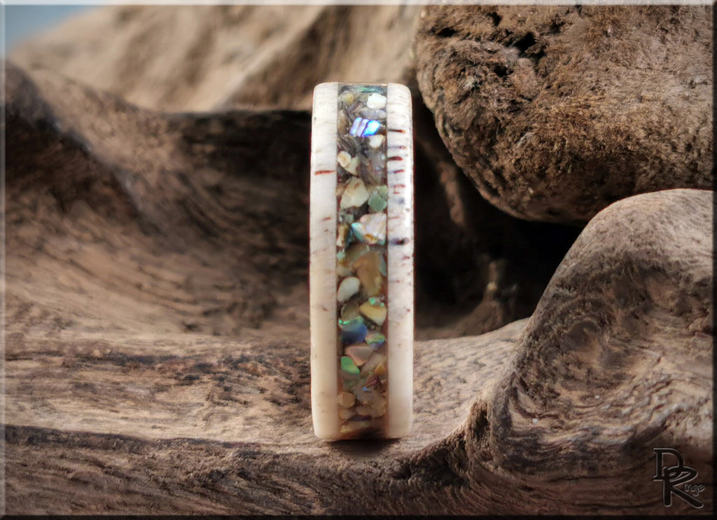 Close-up of handcrafted antler ring with abalone inlay on rustic wooden background by DR Rings