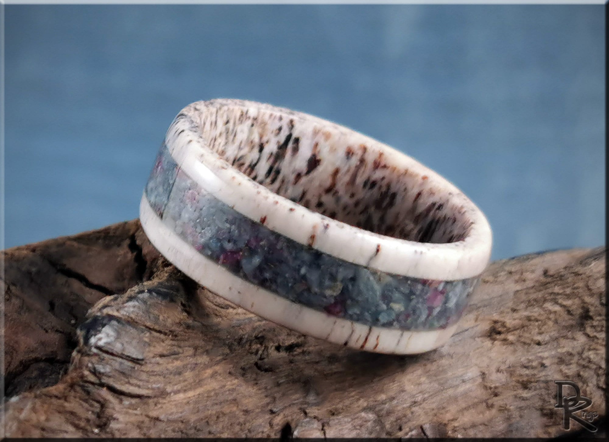 DR Rings antler ring with kyanite and ruby inlay resting on rustic wood background