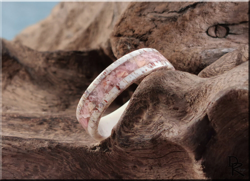Antler Ring with stone inlay featuring pink and white hues displayed on rustic wood