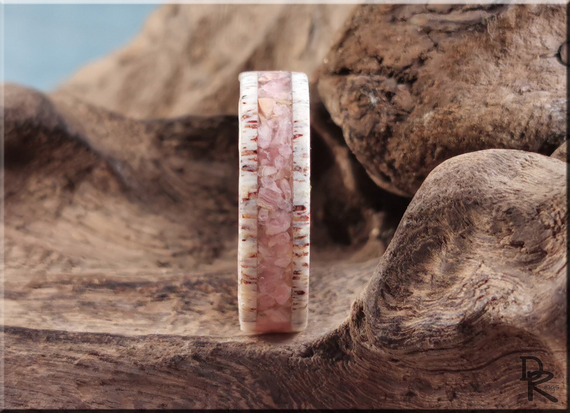 Antler ring with stone inlay featuring pink stone center and natural antler edges on wood background by DR Rings
