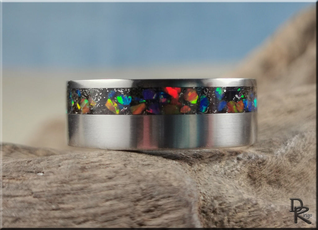 DR Rings titanium ring with meteorite inlay featuring colorful iridescent fragments on a natural background