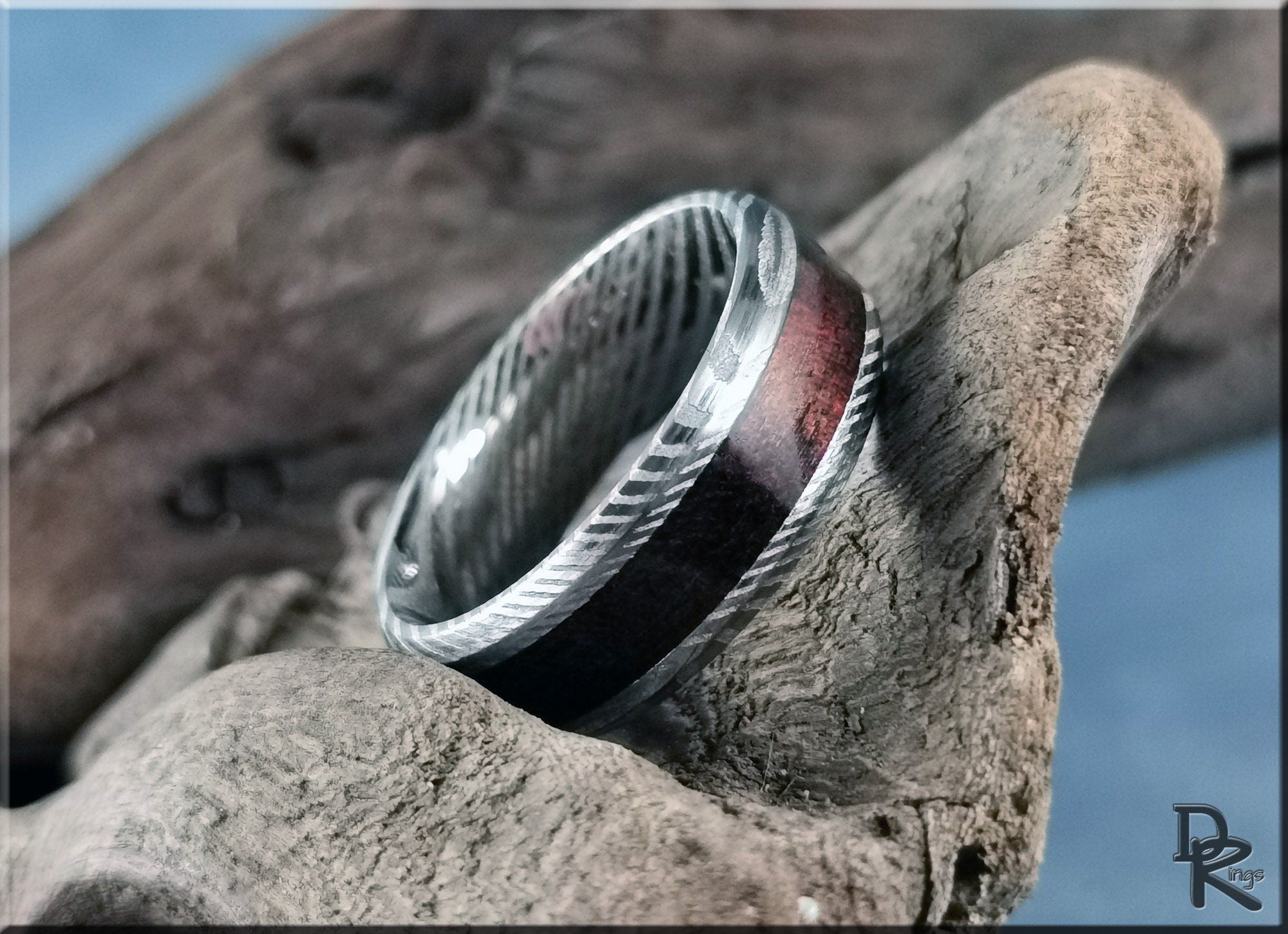Damascus steel ring with wood inlay featuring intricate patterns and a polished wooden center band