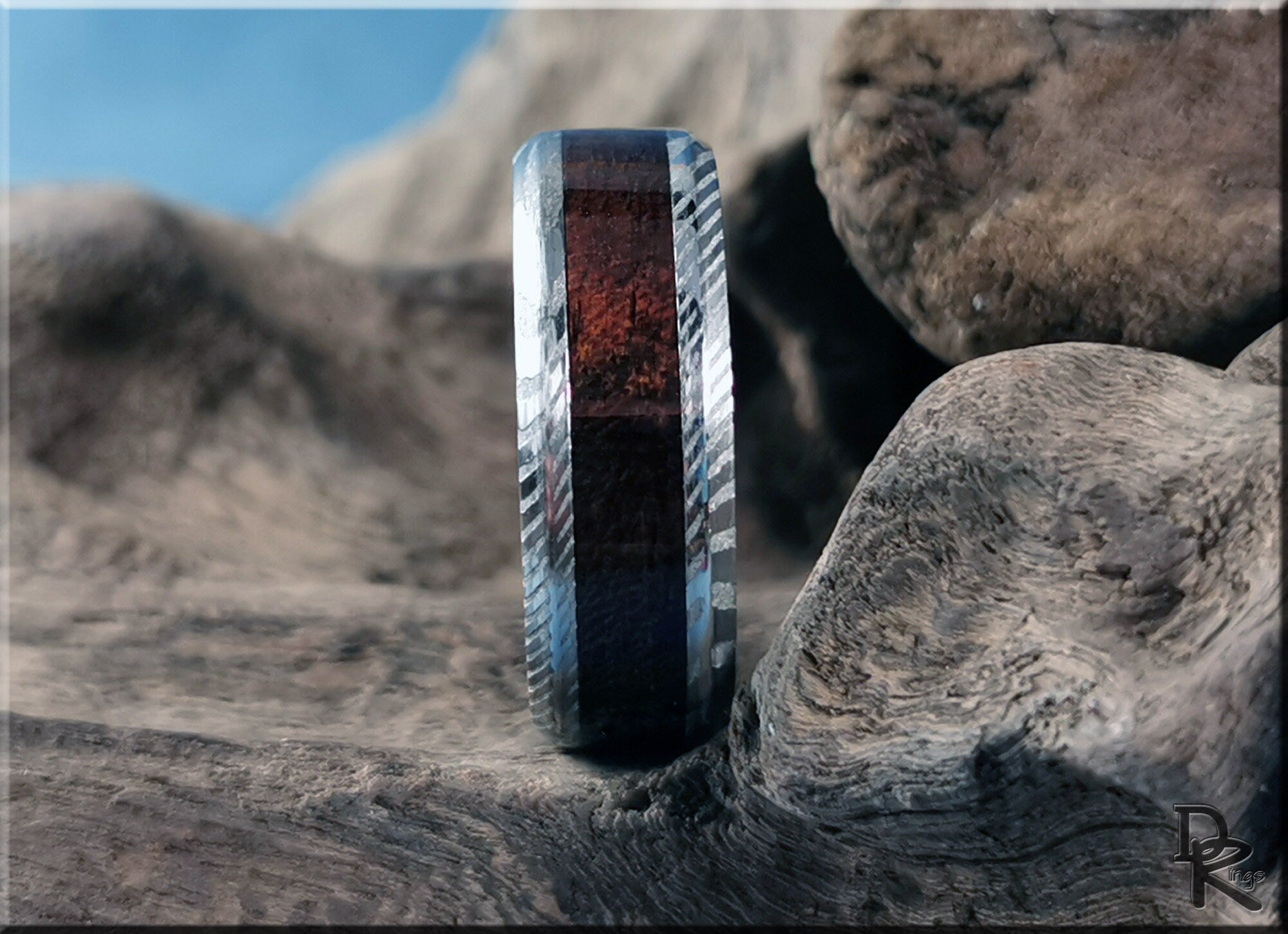 Damascus steel ring with wood inlay standing on natural wood texture background by DR Rings
