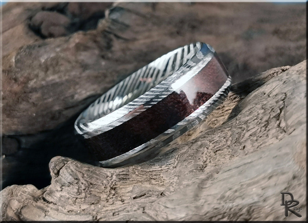 Damascus steel ring with wood inlay by DR Rings displayed on rustic textured wood