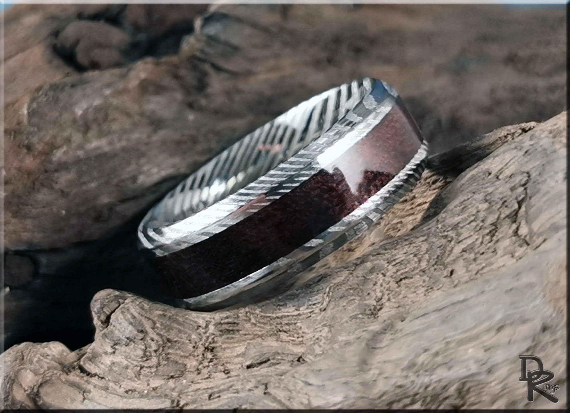 Damascus steel ring with wood inlay by DR Rings displayed on rustic textured wood