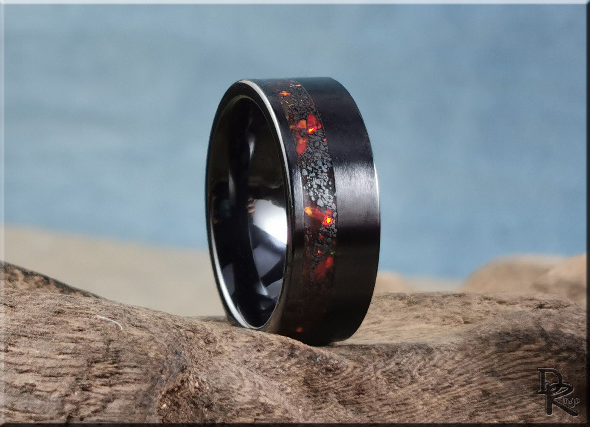 DR Rings black band ring opal with red and orange opal inlay on textured wood background