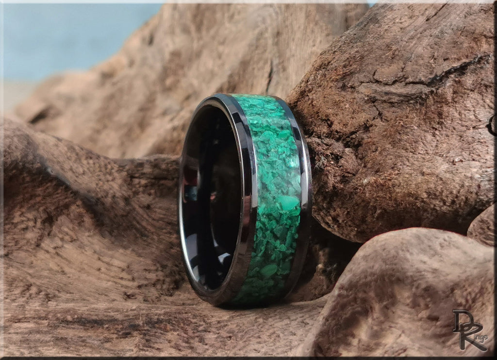 Black ceramic ring with green stone inlay displayed on rustic wooden surface by DR Rings