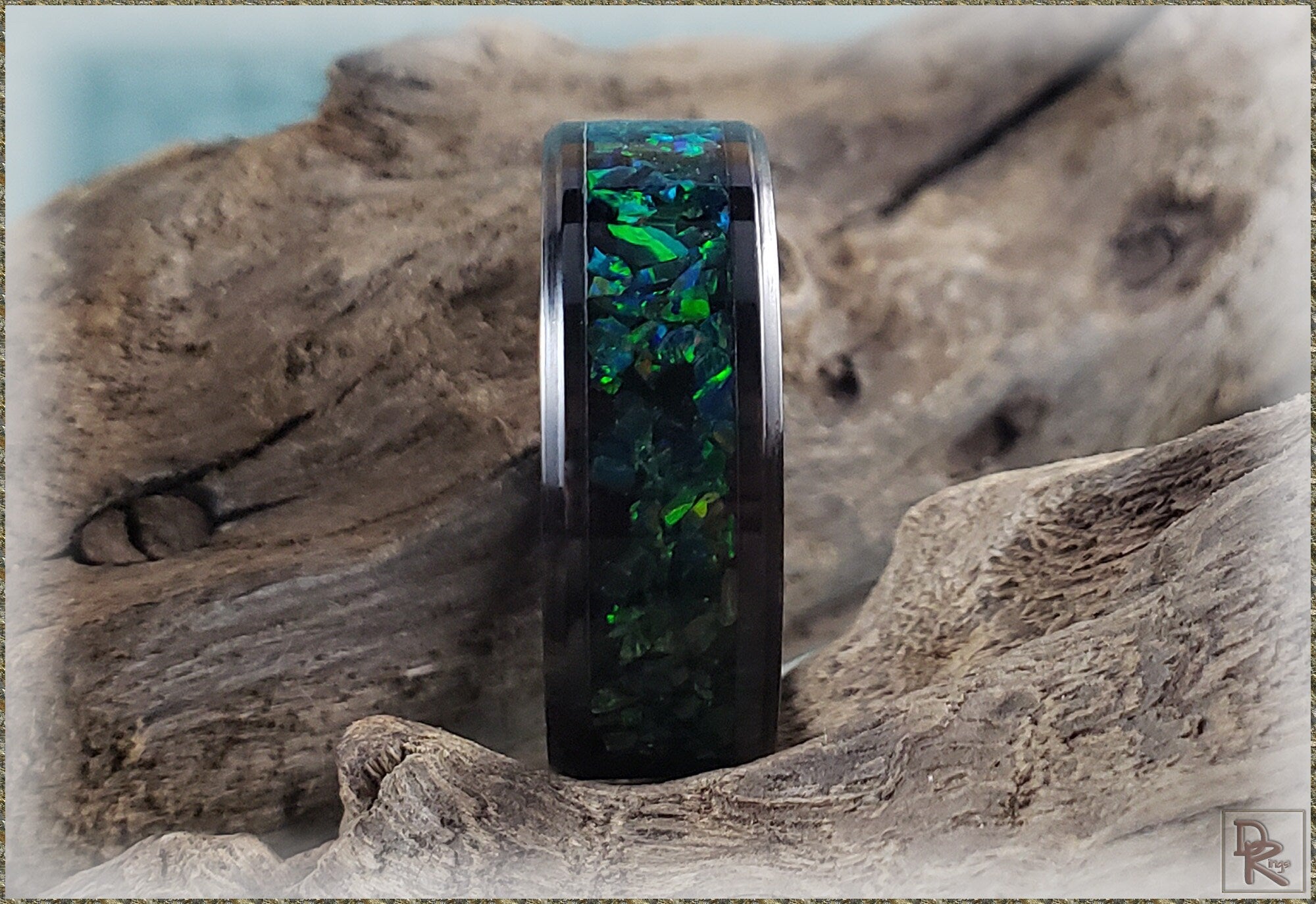 DR Rings ceramic ring with black band and green blue opal inlay on wooden background