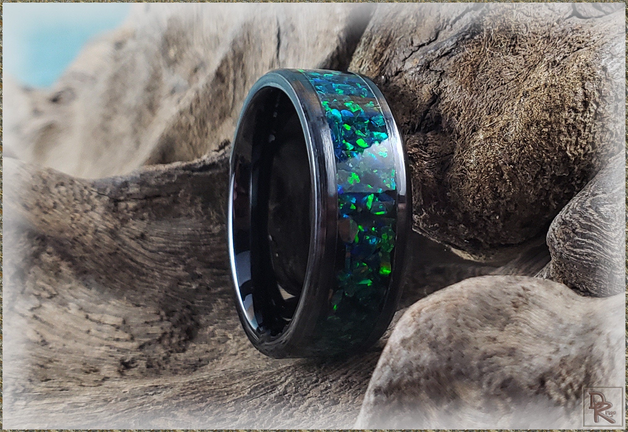 DR Rings black ceramic ring with blue and green iridescent inlay on natural wood background