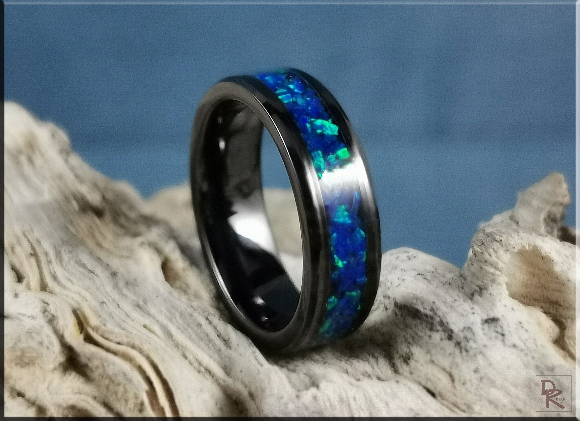 DR Rings ceramic ring with inlay featuring blue opal design on a textured natural surface