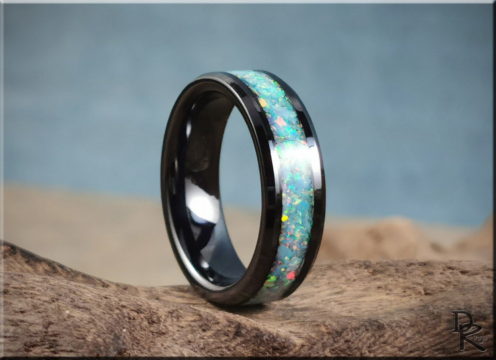Black ceramic ring with inlay featuring colorful opal design by DR Rings on natural wood surface