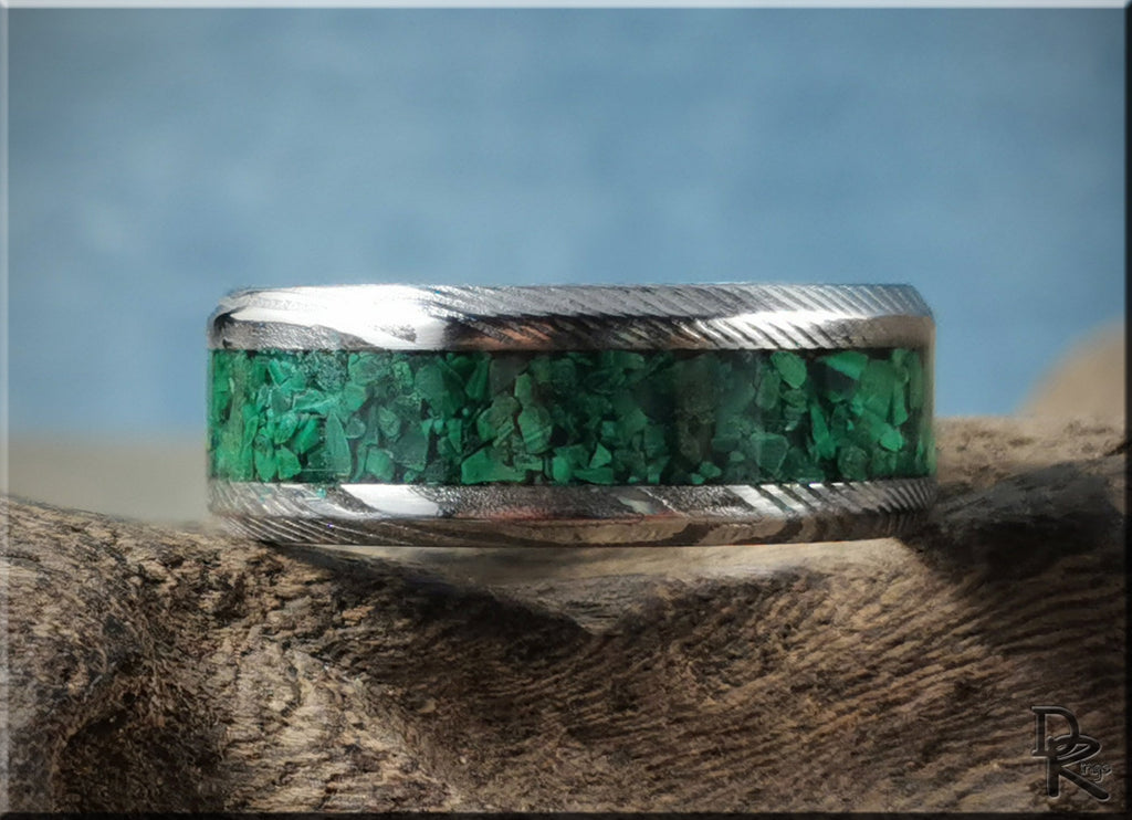 Damascus steel ring with malachite inlay by DR Rings displayed on textured wood